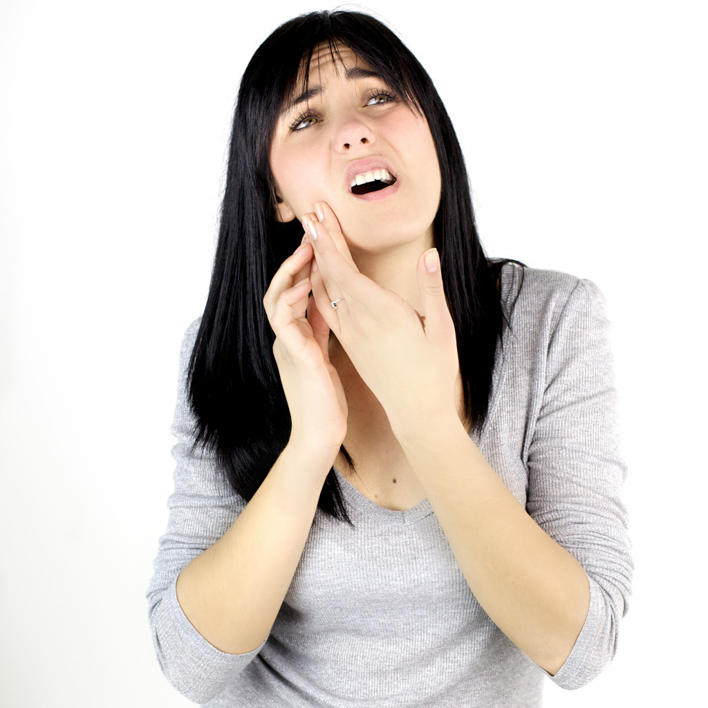 woman clutching her jaw because of tooth ache