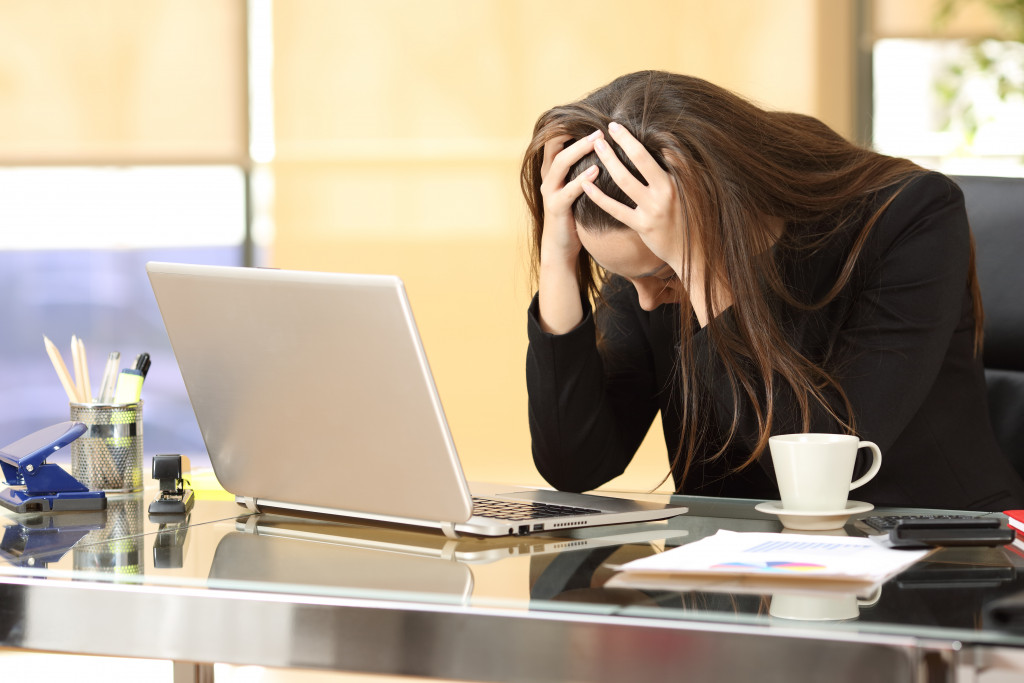 A frustrated young businesswoman holding her head while working in an office