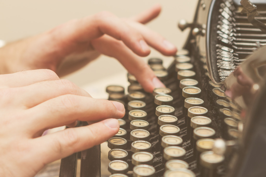 person's hand typing on a typewriter