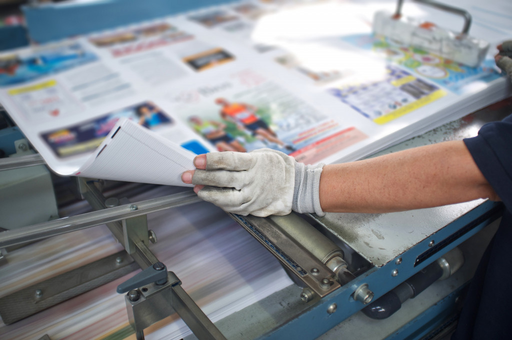 A worker cutting pages of a magazine on a machine cutter