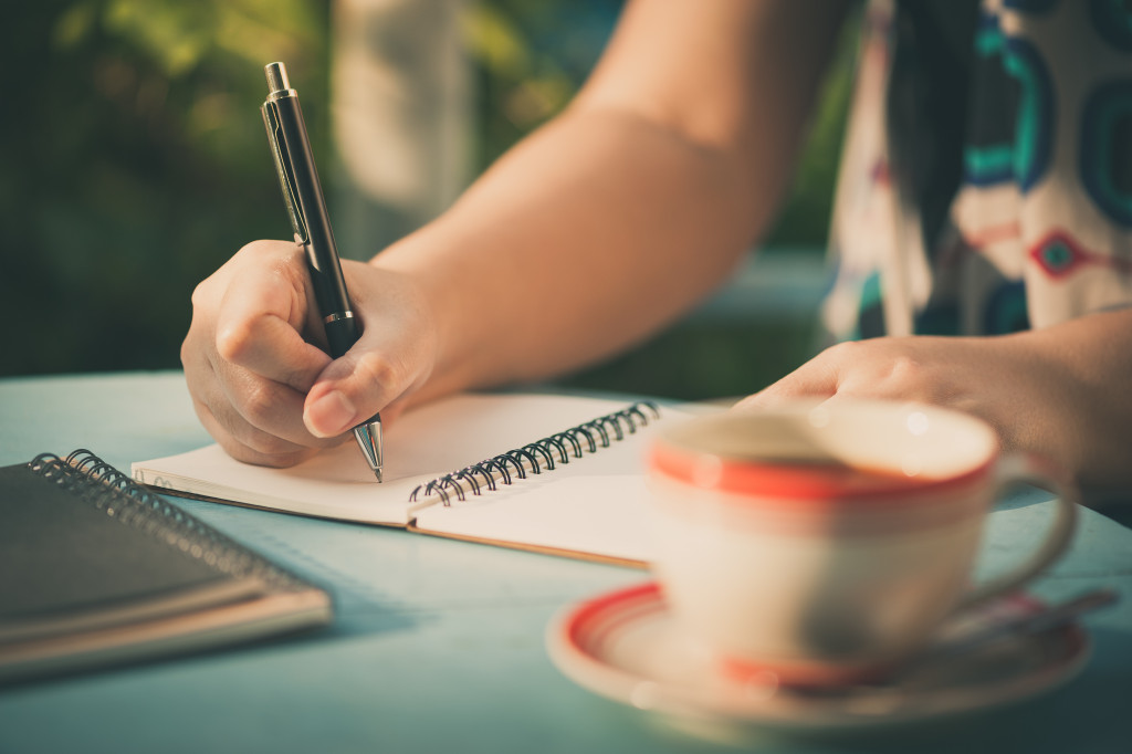 a woman writing on a journal in a cafe